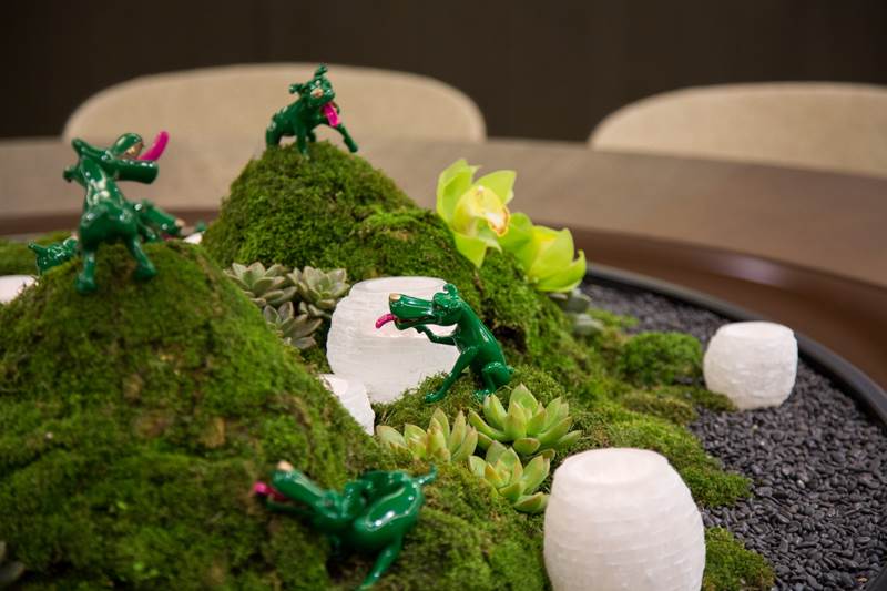 藝術家周春芽綠狗小型雕塑爬上桌面，演繹人生姿態。