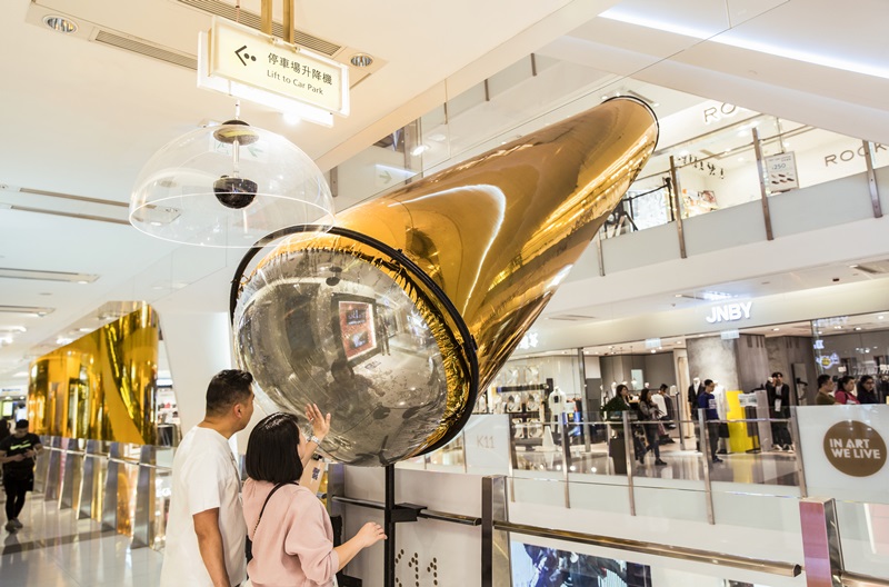 金色充氣物橫跨整個中庭，在不同樓層與扶梯間穿梭。